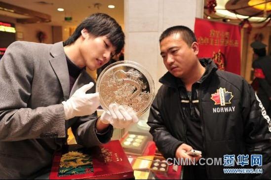 12月21日，工作人員向顧客介紹一款5公斤重的壬辰賀歲紀(jì)念大銀章，其正面的“金龍降喜”圖案，寓意對(duì)龍年萬事亨通的美好祝福。